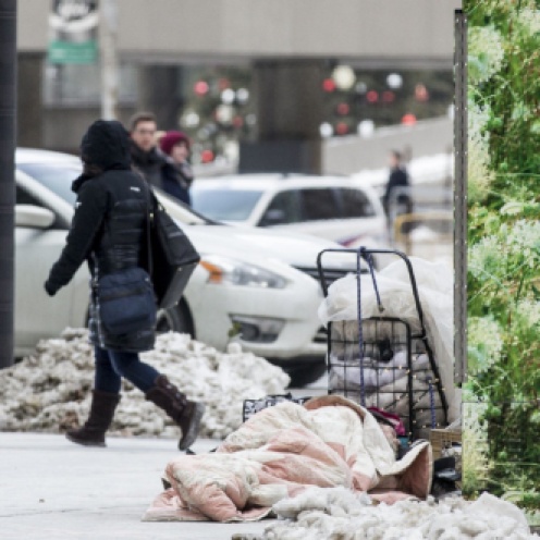 A man sleep on a sidewalk near the intersection of Bay St. and Queen St. W. in downtown Toronto on Wednesday.